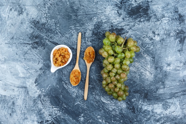 Foto grátis conjunto de passas e uvas verdes em um fundo de gesso sujo. vista do topo.