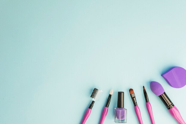 Conjunto de pincéis de maquiagem profissional essenciais; Verniz para unhas e esponja sobre fundo colorido