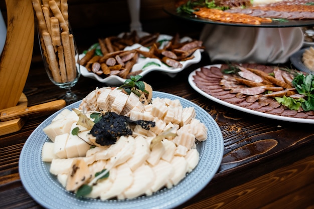 Conjunto de queijo, salsichas e salgadinhos na mesa de madeira