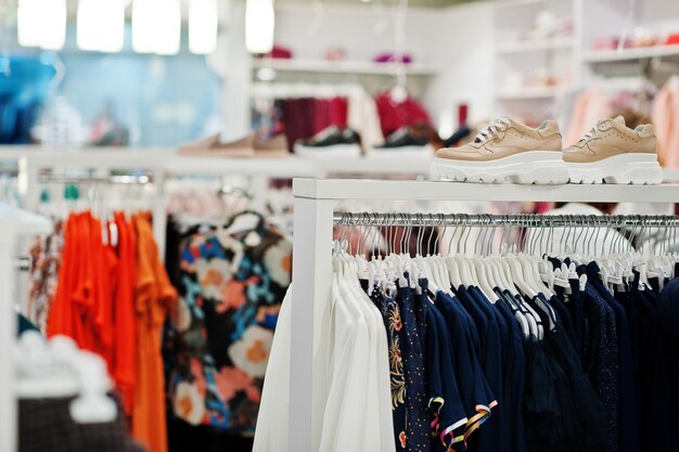 Conjunto de roupas coloridas femininas nas prateleiras com sapatos na loja de roupas nova boutique moderna