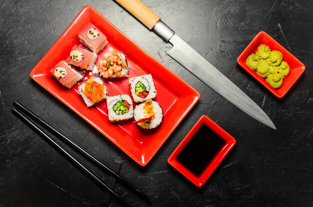 Conjunto de sushi, faca japonesa, pauzinhos e na mesa de pedra escura. Wasabi, molho de soja. Sushi