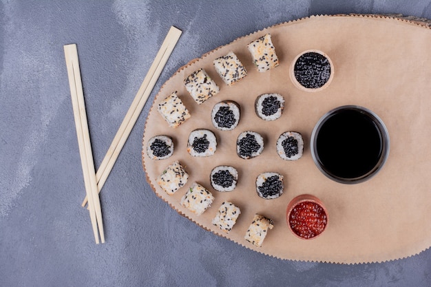 Foto grátis conjunto de sushi. rolos de sushi maki e alaska na placa de madeira com pauzinhos, caviar e molho de soja.