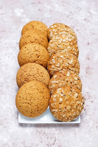 Conjunto de vários biscoitos de estilo americano, sobre um fundo claro e concreto. Pão com confetes, sementes de gergelim, manteiga de amendoim, aveia e biscoitos de chocolate.