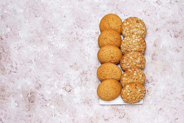 Conjunto de vários biscoitos de estilo americano, sobre um fundo claro e concreto. Pão com confetes, sementes de gergelim, manteiga de amendoim, aveia e biscoitos de chocolate.