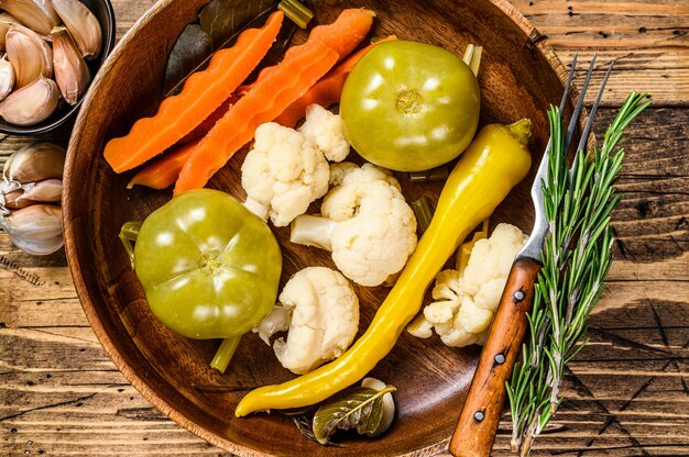 Conservas de legumes salgados e pickles num prato de madeira.