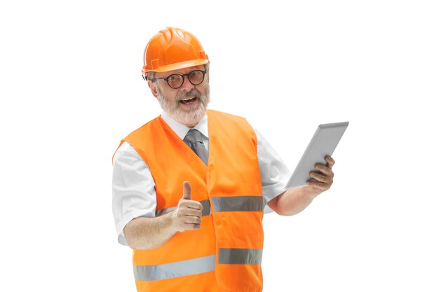 construtor em um colete de construção e capacete laranja com tablet em fundo branco.