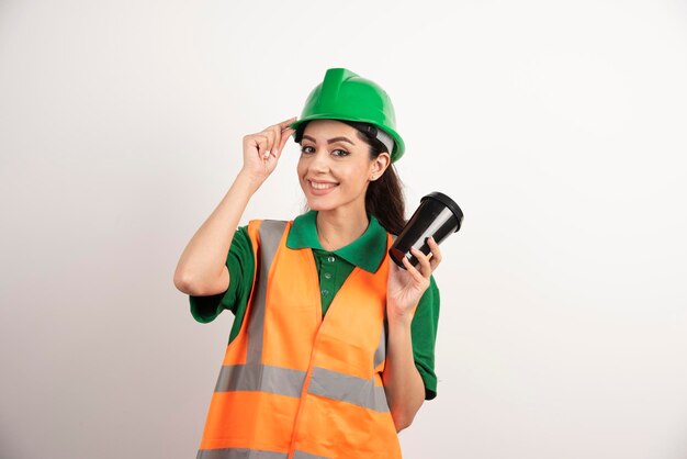 Construtor feminino sorridente com copo preto. Foto de alta qualidade