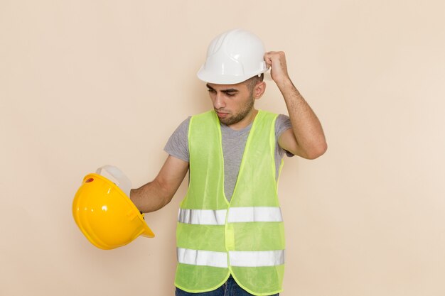 Construtor masculino de vista frontal com capacete branco posando em fundo claro