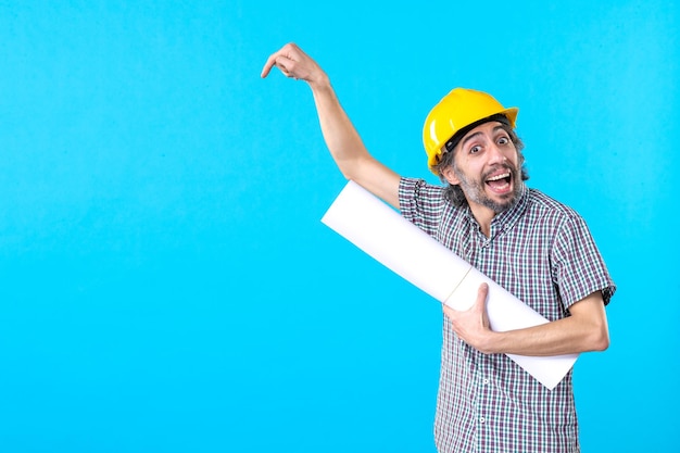 Foto grátis construtor masculino de vista frontal com plano em suas mãos sobre fundo azul engenheiro trabalhador construtor trabalho arquitetura de propriedade