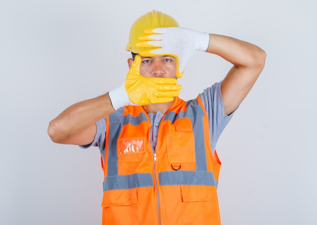 Foto grátis construtor masculino olhando através do quadro formado pelas mãos em vista frontal uniforme.