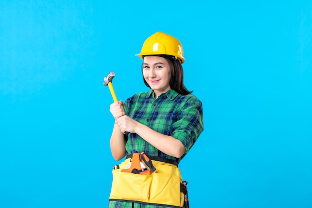 Construtora de frente, de uniforme, segurando um martelo no azul