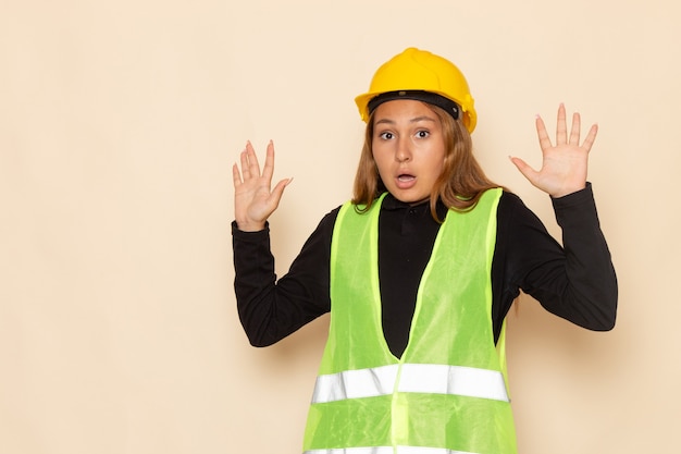 Foto grátis construtora feminina com capacete amarelo e camisa preta posando com as mãos levantadas na mesa branca construtora feminina construtora