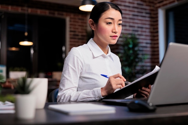 Consultor financeiro com área de transferência revisando a papelada da campanha de marketing enquanto analisa os dados contábeis. Empregado da empresa de negócios no espaço de trabalho do escritório assinando a documentação do projeto de inicialização.