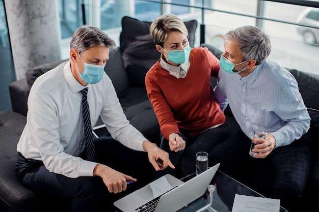 Consultor financeiro e casal usando máscaras enquanto usa laptop em uma reunião