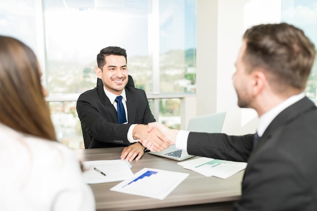 Consultor financeiro selando um acordo com clientes na mesa no escritório