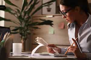 Foto grátis contabilista feminina calculando contas de impostos enquanto trabalhava em finanças no escritório
