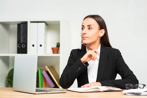 Contemplado, jovem, executiva, sentando, em, a, escrivaninha escritório, com, laptop, escrivaninha