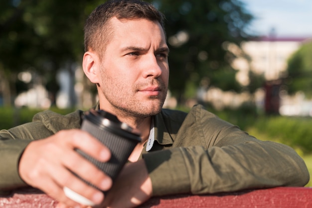 Foto grátis contemplando o homem segurando o copo de café descartável no parque