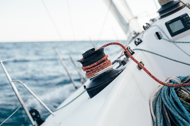 Convés de um veleiro profissional ou iate de corrida durante a competição em um dia ensolarado e ventoso de verão, movendo-se rapidamente através das ondas e da água, com a spinnaker levantada