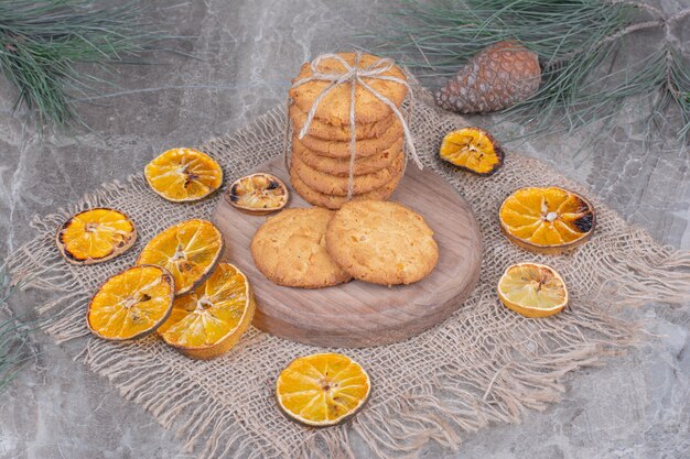 Cookies amarrados com um fio em uma placa de madeira com rodelas de laranja secas