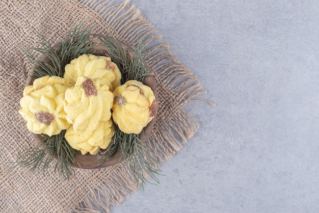 Foto grátis cookies aninhados em uma tigela de folhas de pinheiro na mesa de mármore.