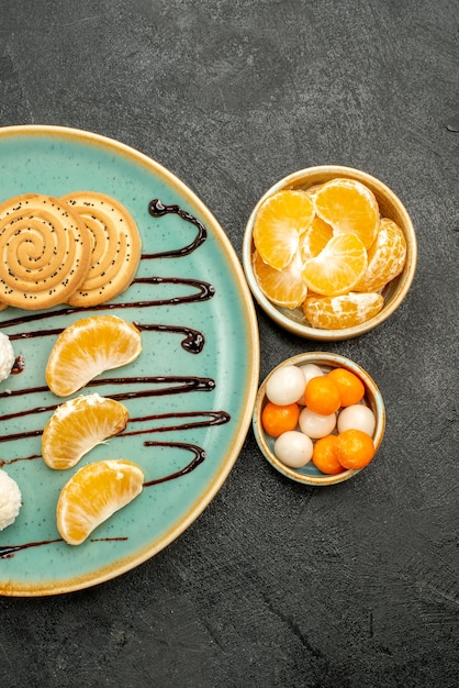 Cookies de açúcar de vista superior com doces de tangerinas em fundo cinza