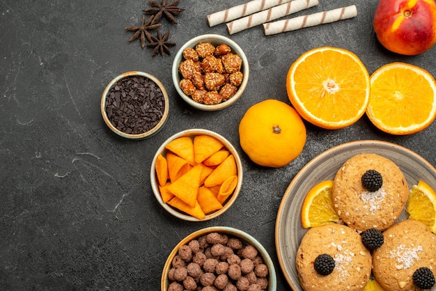 Cookies de areia com fatias de laranja na superfície cinza-escuro de cima