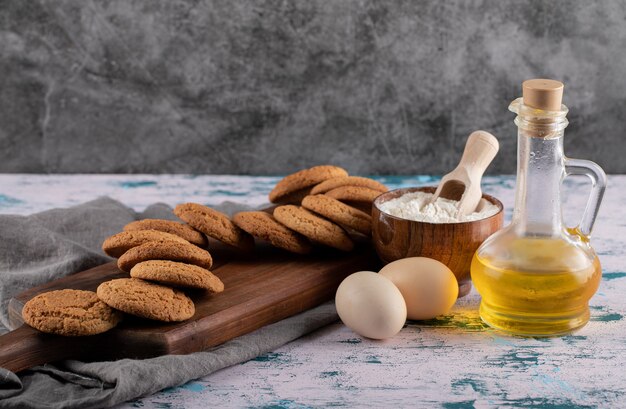 Cookies de aveia em uma travessa de madeira com ingredientes ao redor.