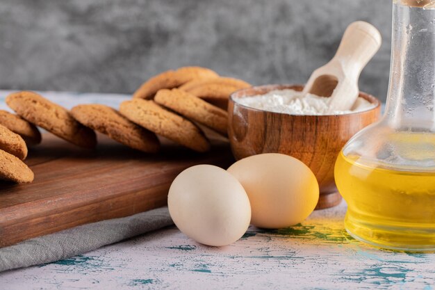 Cookies de aveia em uma travessa de madeira com ingredientes ao redor.