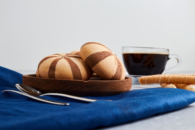 Foto grátis cookies de cacau com uma xícara de café na toalha de mesa azul.