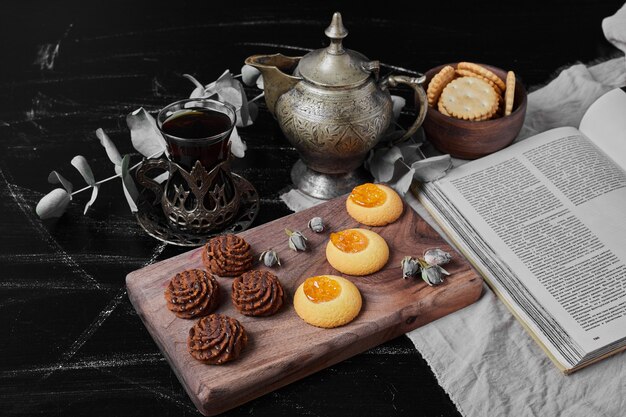 Cookies de cacau e manteiga em uma placa de madeira com chá.