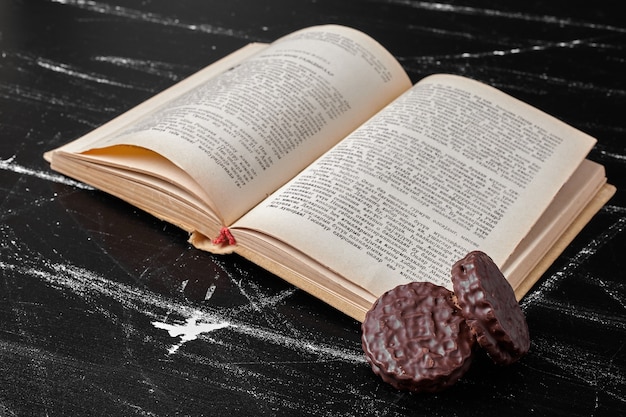 Foto grátis cookies de chocolate com um livro antigo à parte.