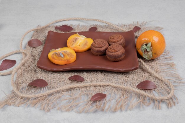 Cookies de chocolate e fatias de caqui no prato. Foto de alta qualidade