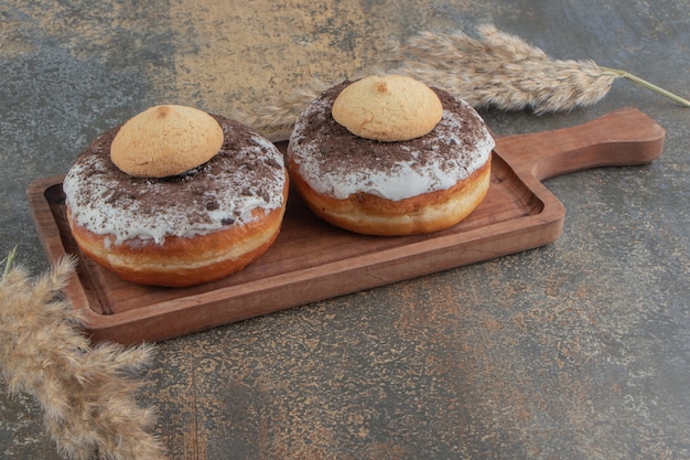 Foto grátis cookies em cima de donuts na placa de madeira na mesa de madeira