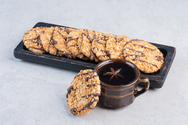 Foto grátis cookies em uma pequena bandeja ao lado de uma xícara de chá na mesa de mármore.