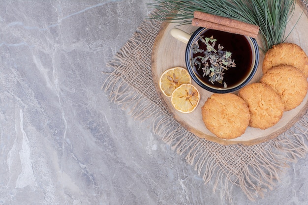 Cookies em uma travessa de madeira com uma xícara de glintwine e rodelas de limão ao redor