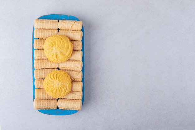 Foto grátis cookies em waffle rola na bandeja de madeira, o mármore.