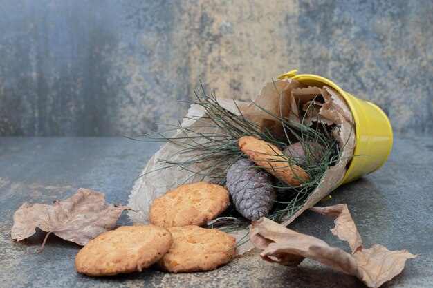 Cookies, grama e pinhas em um balde na mesa de mármore. Foto de alta qualidade