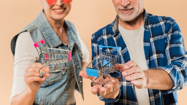 Foto grátis cool casal sênior com carrinhos de compras