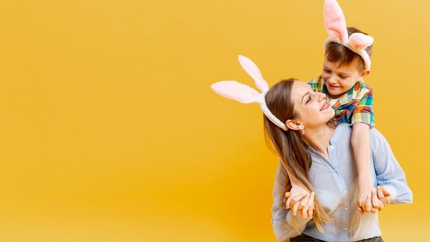 Cópia-espaço mãe e filho com orelhas de coelho, olhando um ao outro