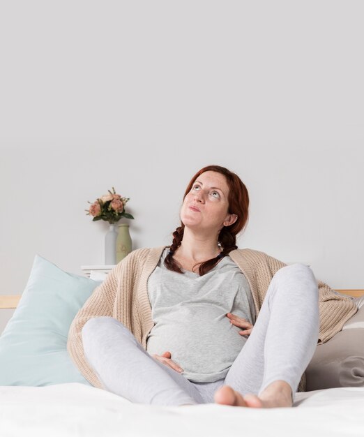 Cópia-espaço mulher grávida em casa na cama