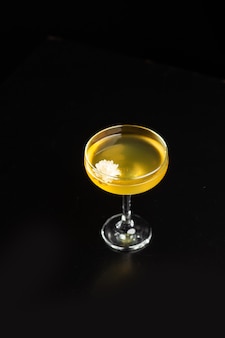 Copo com coquetel de limão amarelo no bar em um fundo preto onde as bebidas são decoradas
