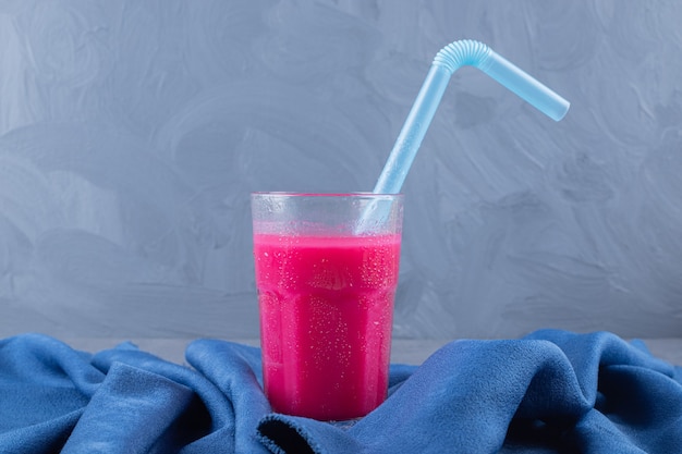 Copo com saboroso smoothie de morango sobre fundo azul.