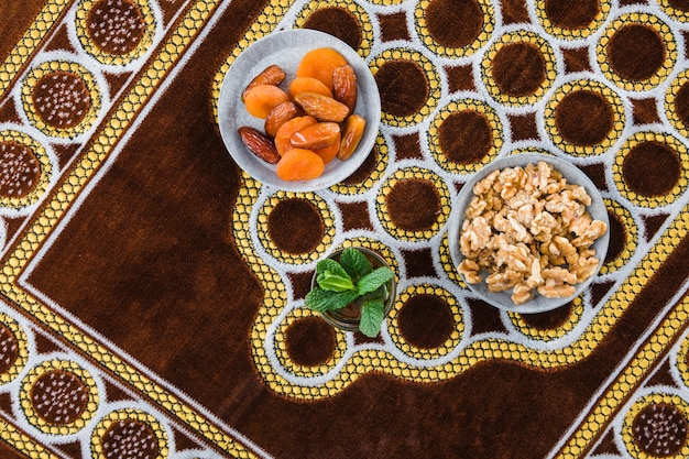 Foto grátis copo de bebida perto de frutos secos e nozes na esteira