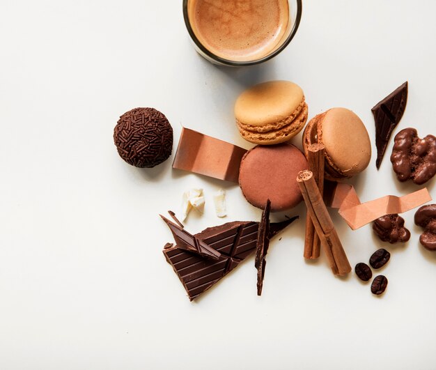 Copo de café; macaroons e pedaço de chocolate com ingredientes em fundo branco