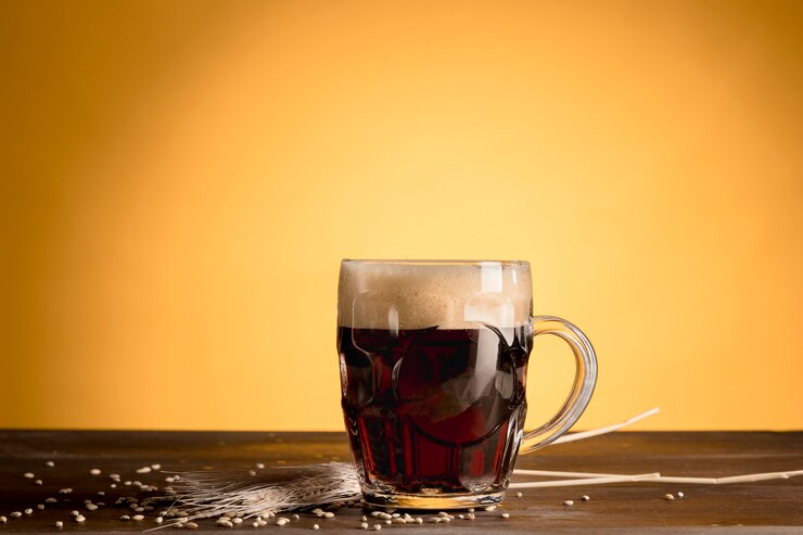 Foto grátis copo de cerveja com cevada de espiga na mesa de madeira