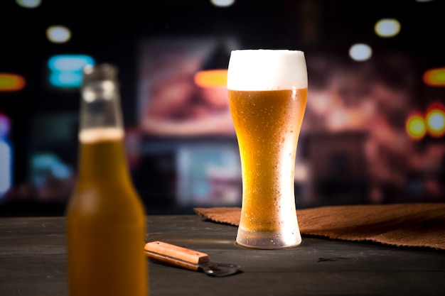 Foto grátis copo de cerveja com garrafa desfocada