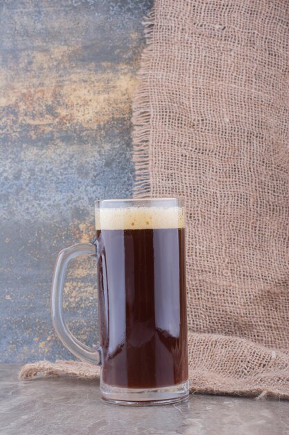 Copo de cerveja escura na mesa de mármore. Foto de alta qualidade