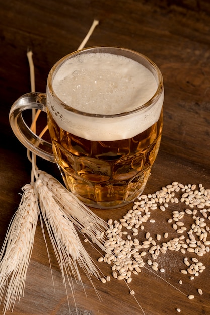 Foto grátis copo de cerveja light com cevada de espiga na mesa de madeira