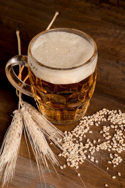 Copo de cerveja light com cevada de espiga na mesa de madeira